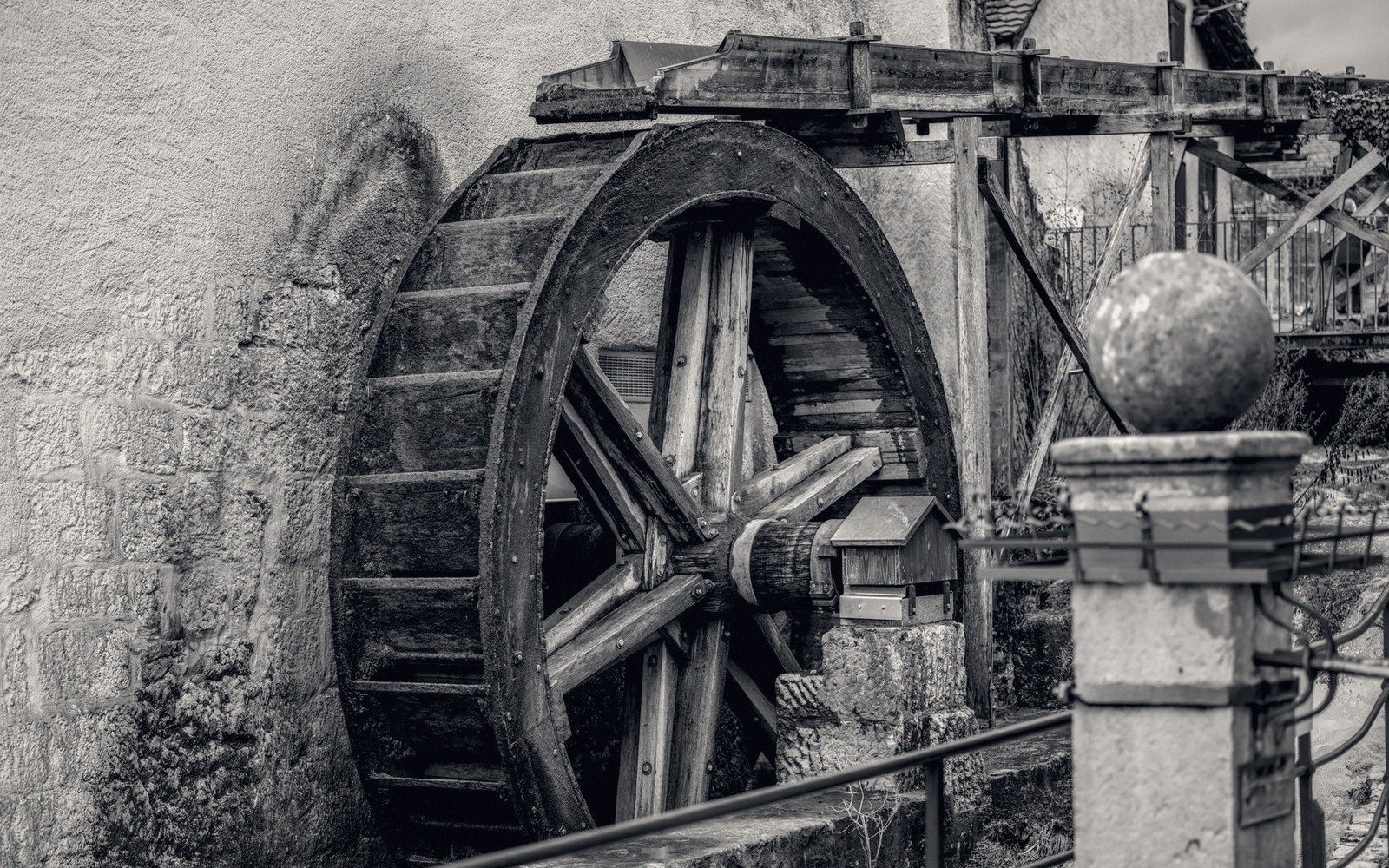 Wooden waterwheel mounted against a stone mill building's wall