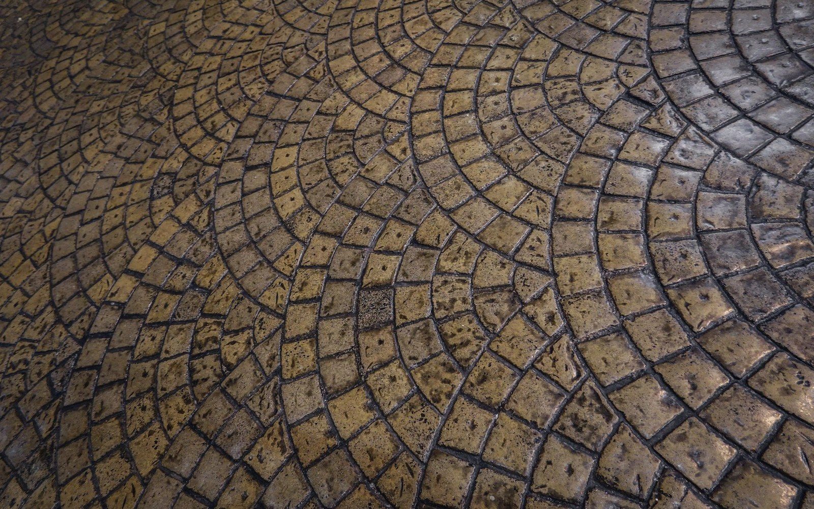 Cobblestones arranged in overlapping fan-shaped patterns forming a paved surface